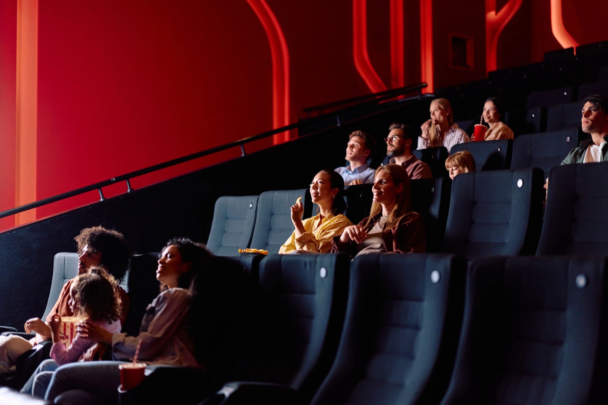 Audience watching movie at modern cinema theater eating snacks